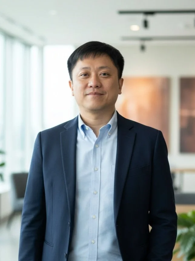 Businessman in a suit standing in a modern office with large windows and artwork in the background