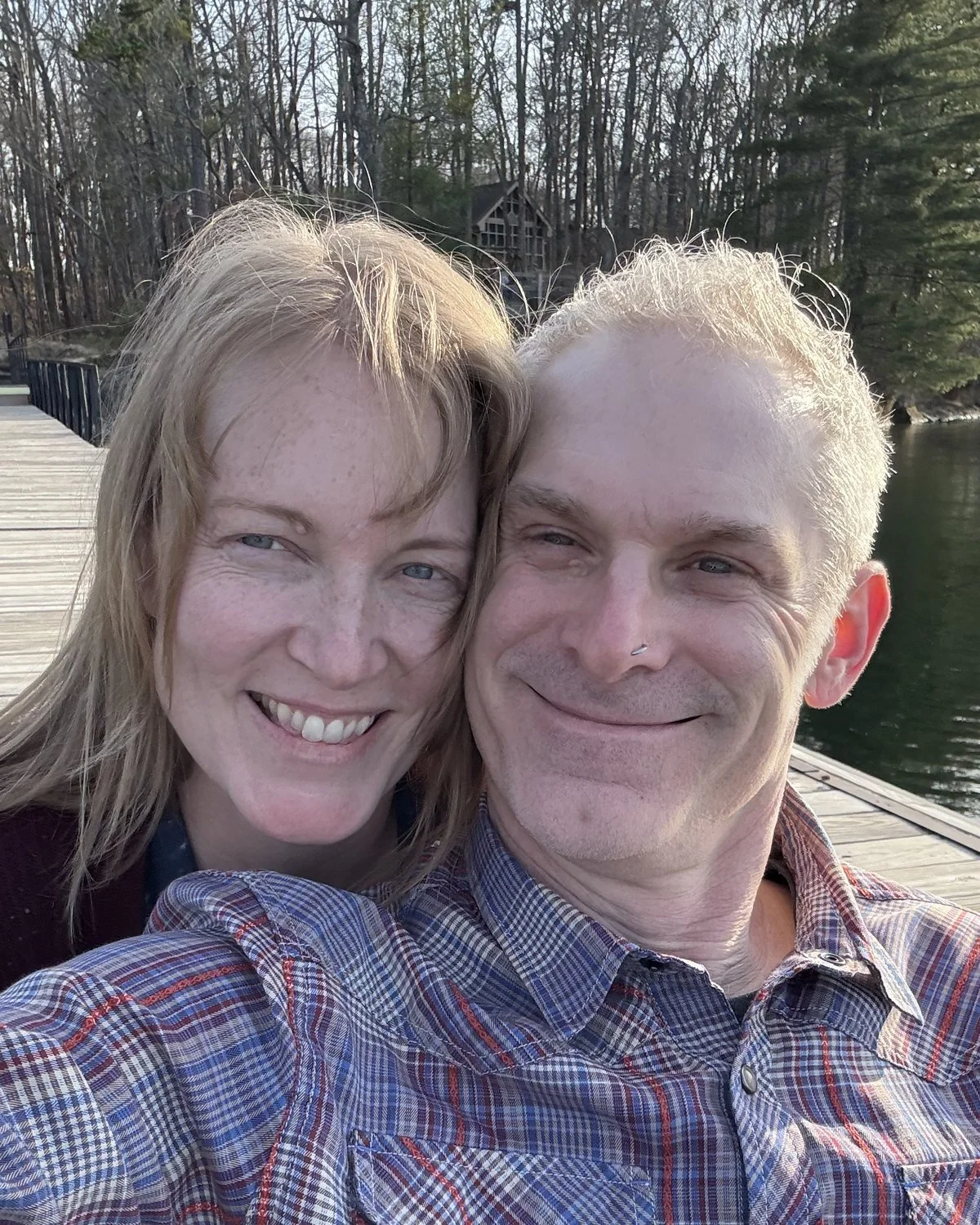 Christine and Brent of Everbound Studio, Gen X husband-and-wife UGC creators, taking a selfie on a lake dock