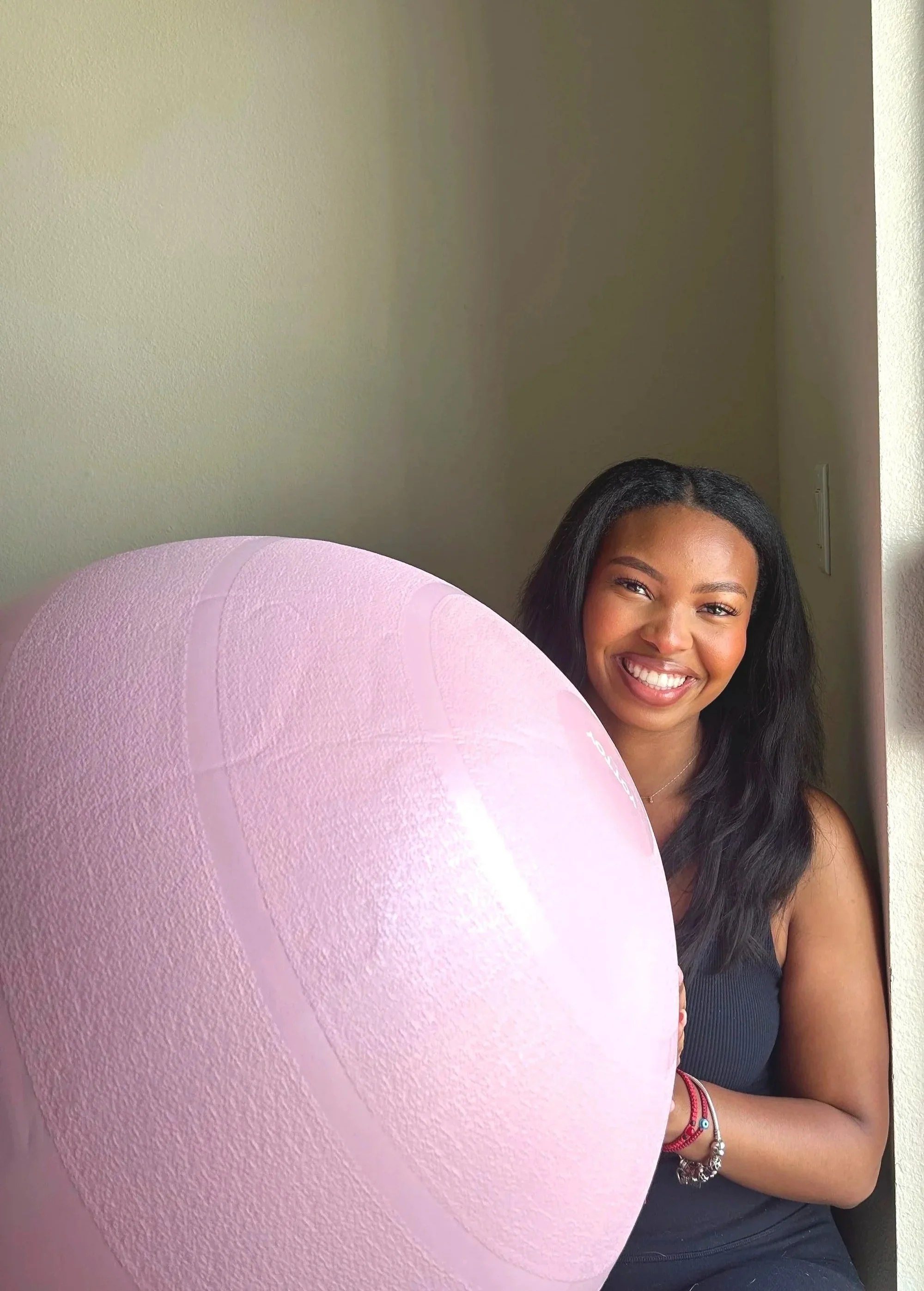 A young Houston Birth Doula with long black hair smiling while holding a pink Birth ball in front of her.

Serened Birthing Houston Doula Services available for Houston area pregnant people