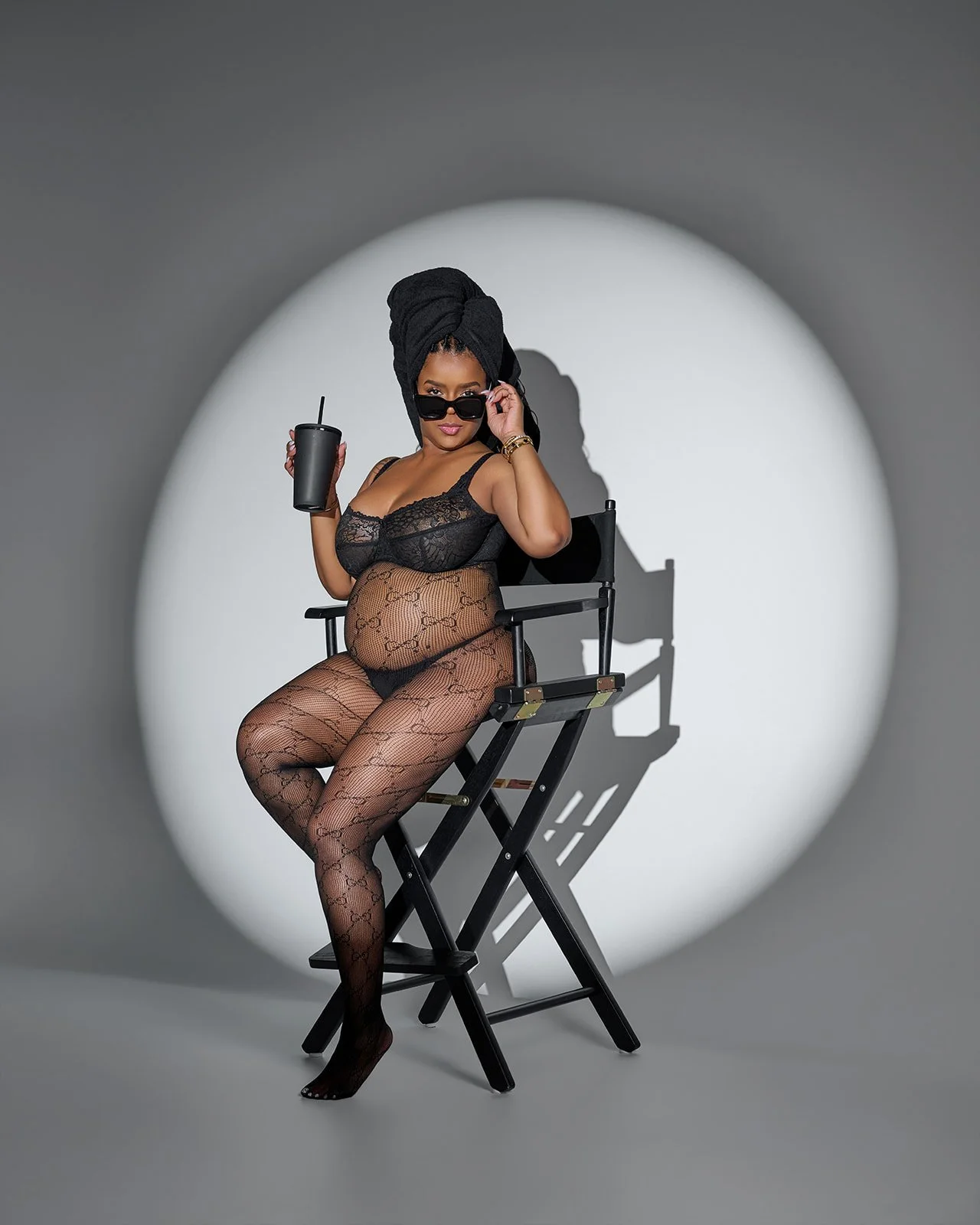 Pregnant woman posing in black lace under a dramatic spotlight during an editorial maternity photography session in Houston.