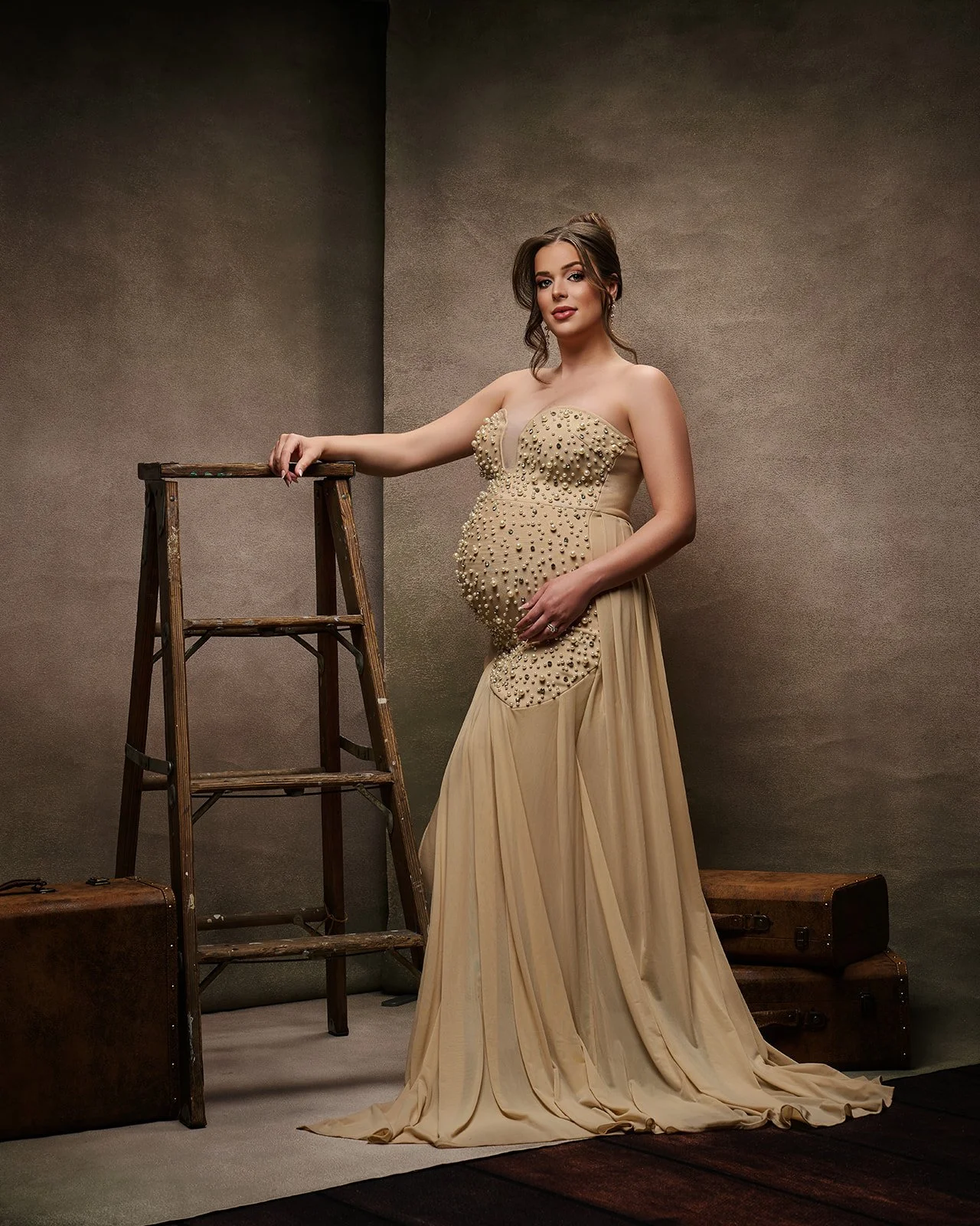 Pregnant woman wearing an elegant beaded neutral gown in a styled fine art maternity photography session in Houston.