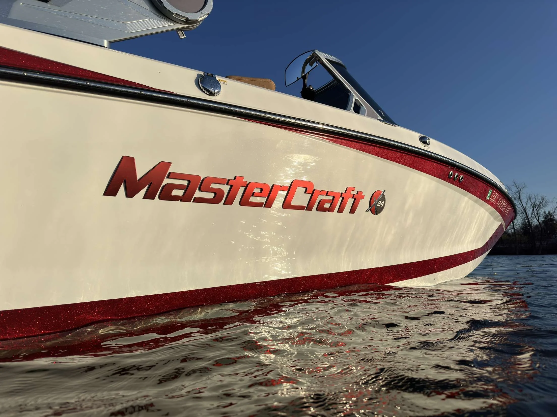 A boat on the water with the brand name "MasterCraft" visible on the side, under a clear blue sky.
