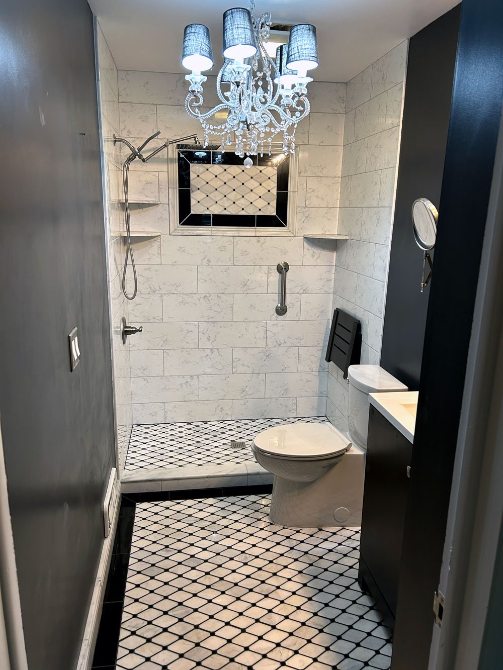 Bathroom with shower, toilet, black cabinet, diamond-patterned black and white floor tiles, chandelier, and a small window with decorative tile framing.