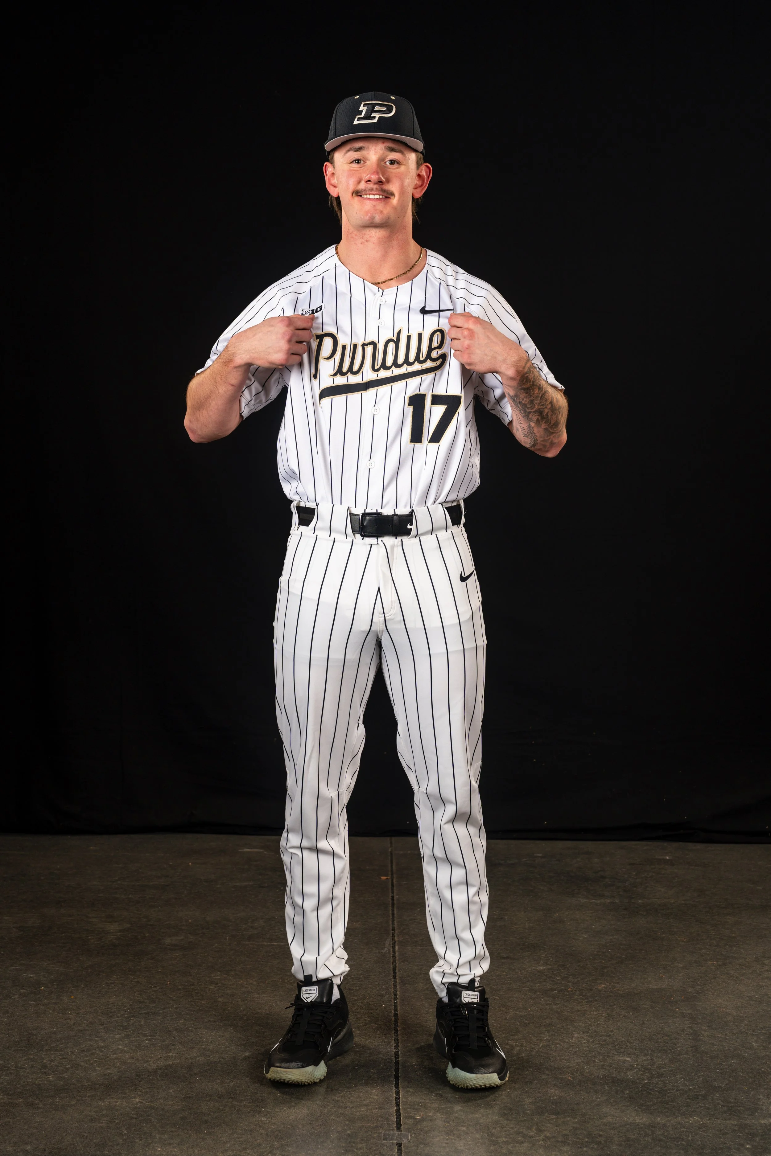 A baseball player wearing a black cap with 'P' logo, white pinstripe uniform with 'Purdue' and number 17, standing against a black background.
