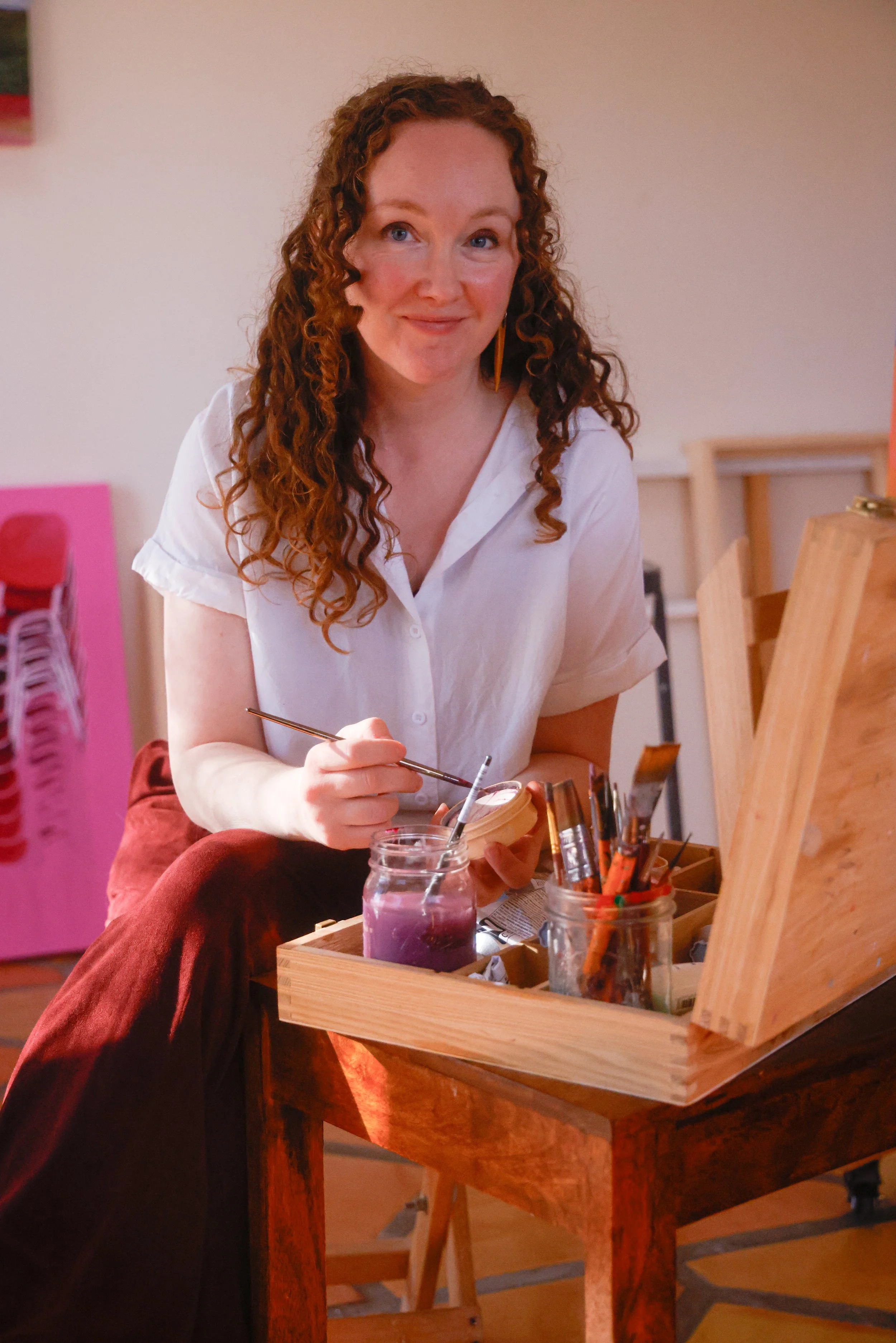 Mujer con cabello rizado de cabello rojo pintando en su estudio de arte