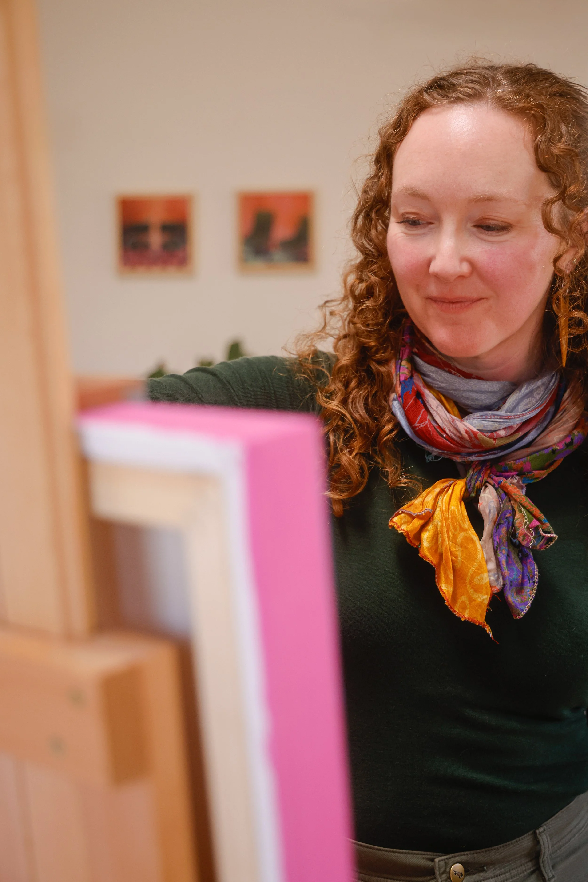 Mujer con cabello rizado, usando bufanda colorida, colocando libros en una estantería.