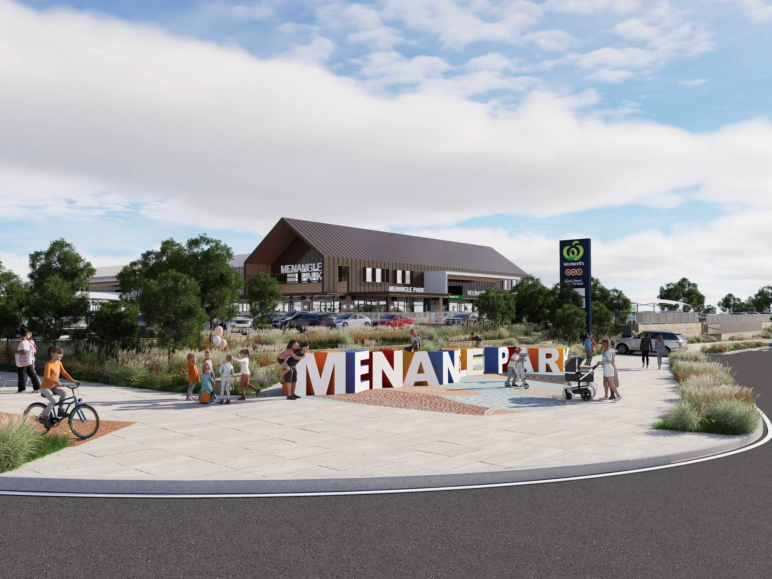 Children and adults gather in front of an entrance named Menangle Park, with a large colorful sign and a modern building above. The area is decorated with balloons and greenery, with trees and a cloudy sky overhead.
