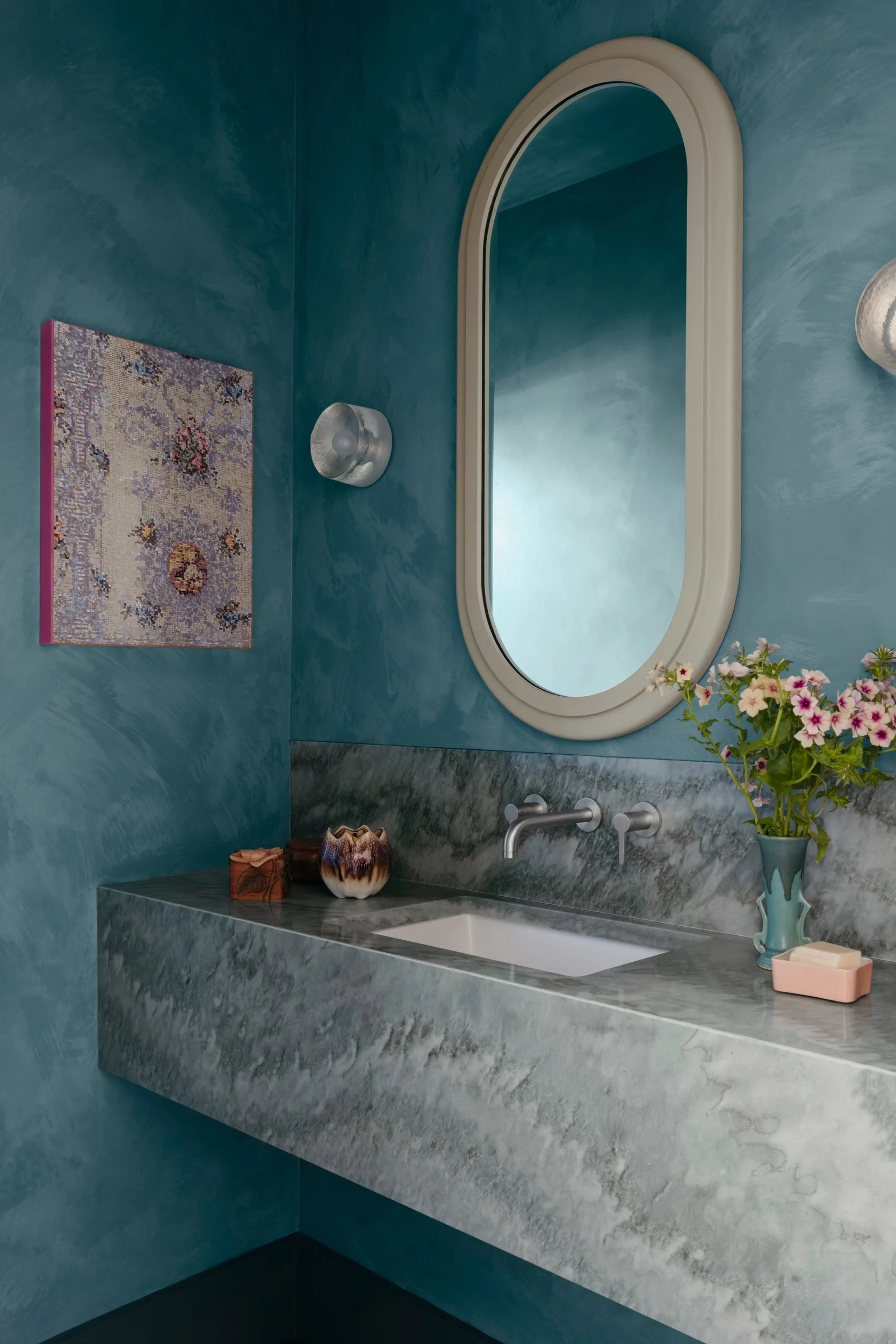 Powder room in teal and mint green limewash with a floating stone vanity, a mint green wood mirror and artwork by Kirsten Lamb