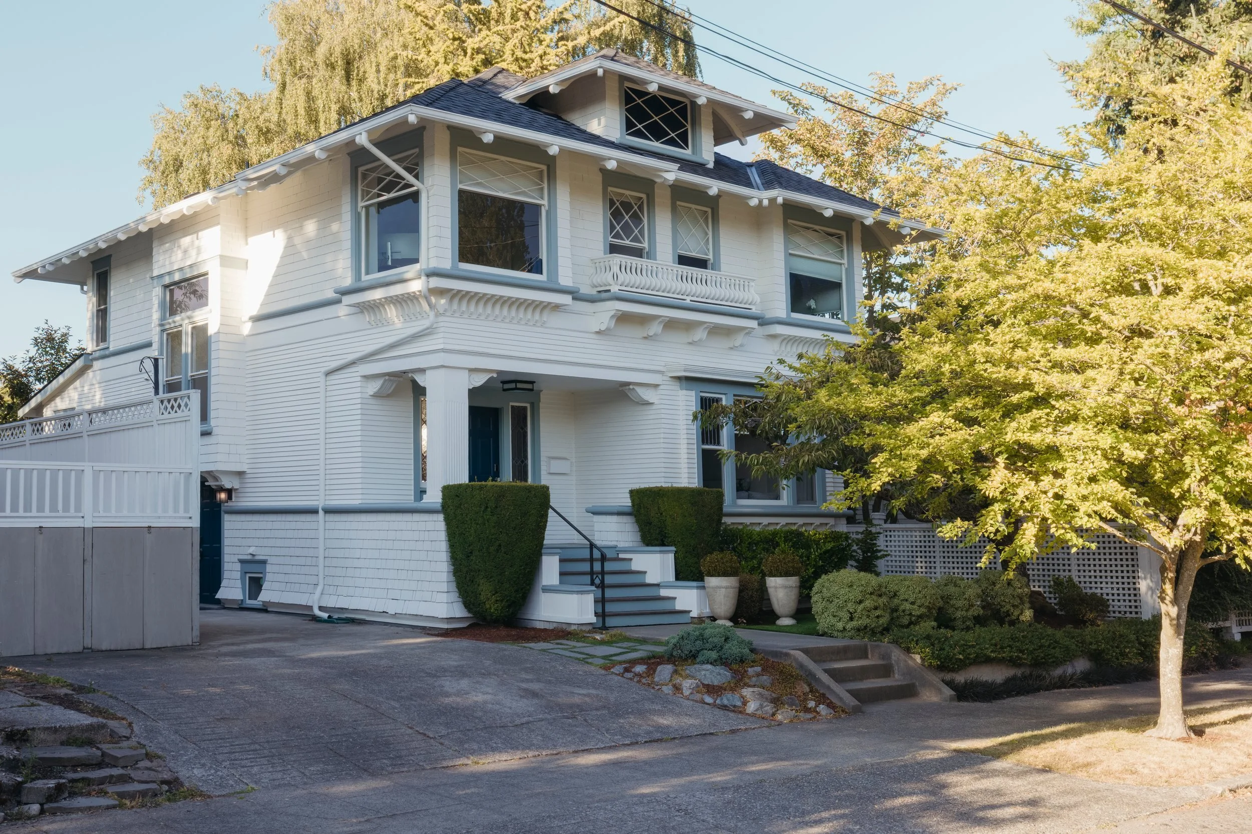 Exterior of the white Queen Anne Foursquare with blue-gray trim and a front porch