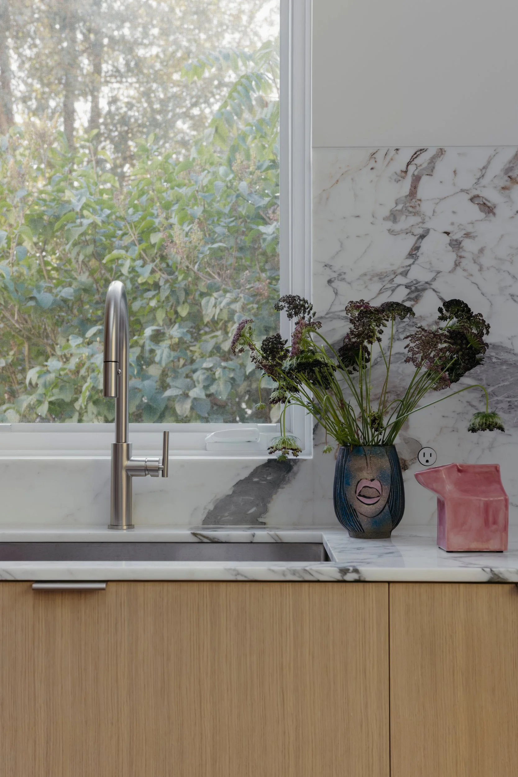 Kitchen sink with a marble backsplash and a window onto the garden