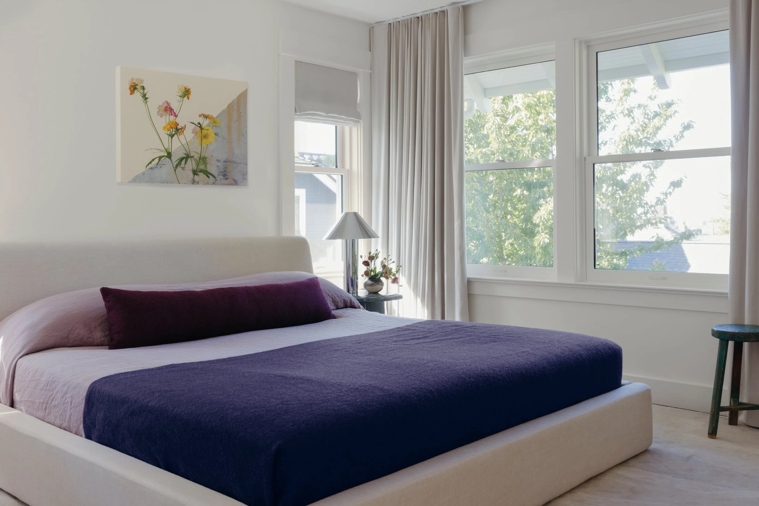 Bedroom with a simple linen bed, vintage bedding, soft taupe linen drapery and custom artwork by Will Brown