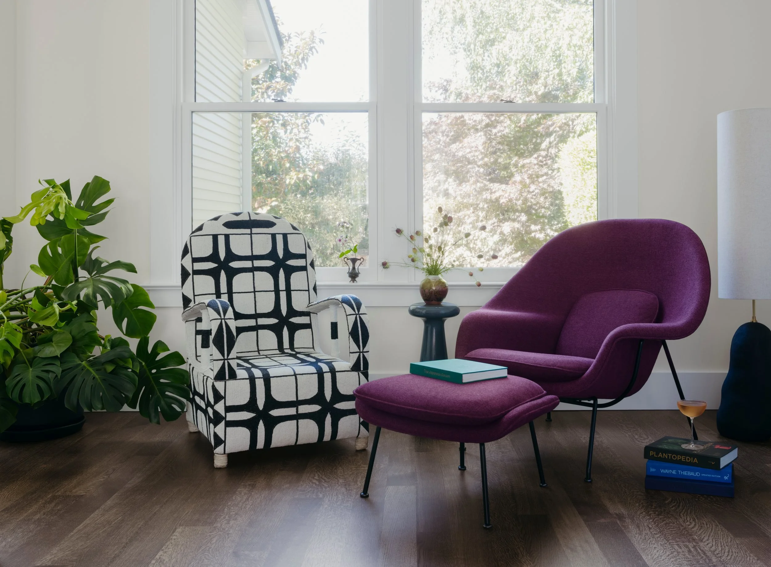 Reading room with a burgundy Womb chair and ottoman beside a hand-beaded black and white chair
