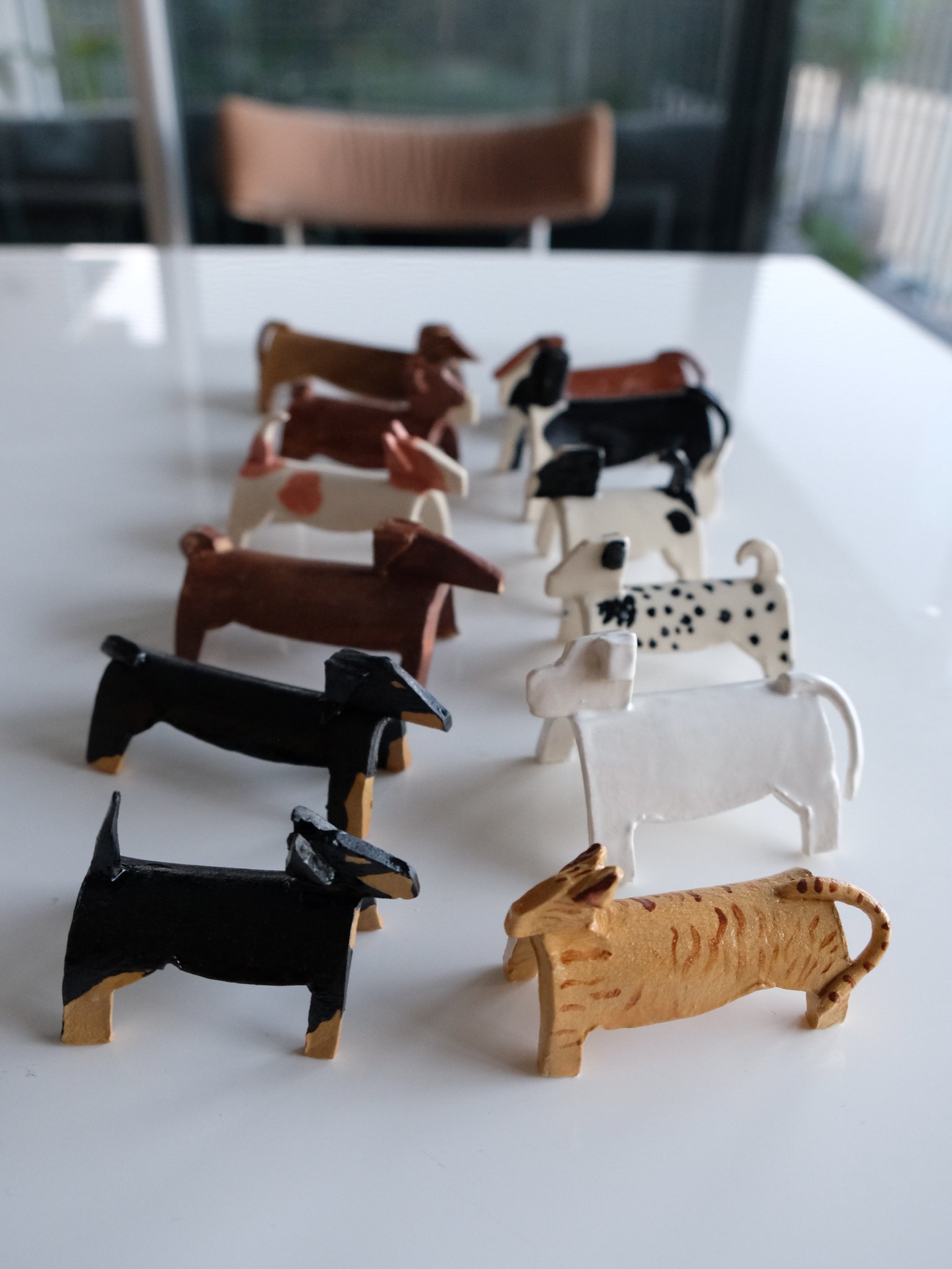 A collection of small, ceramic dog figurines arranged in rows on a white table.