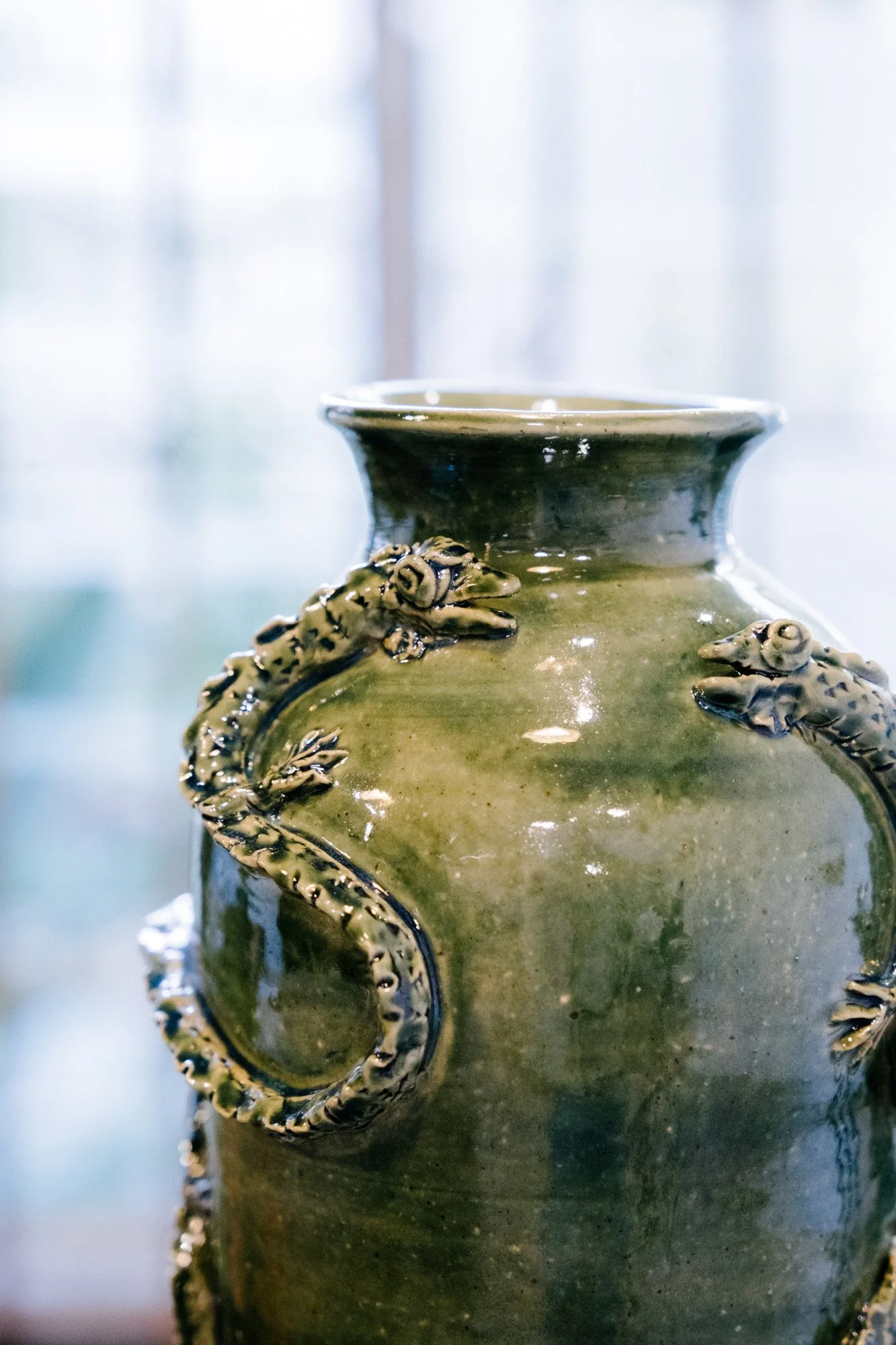 A green ceramic vase with detailed dragon sculptures on its sides.