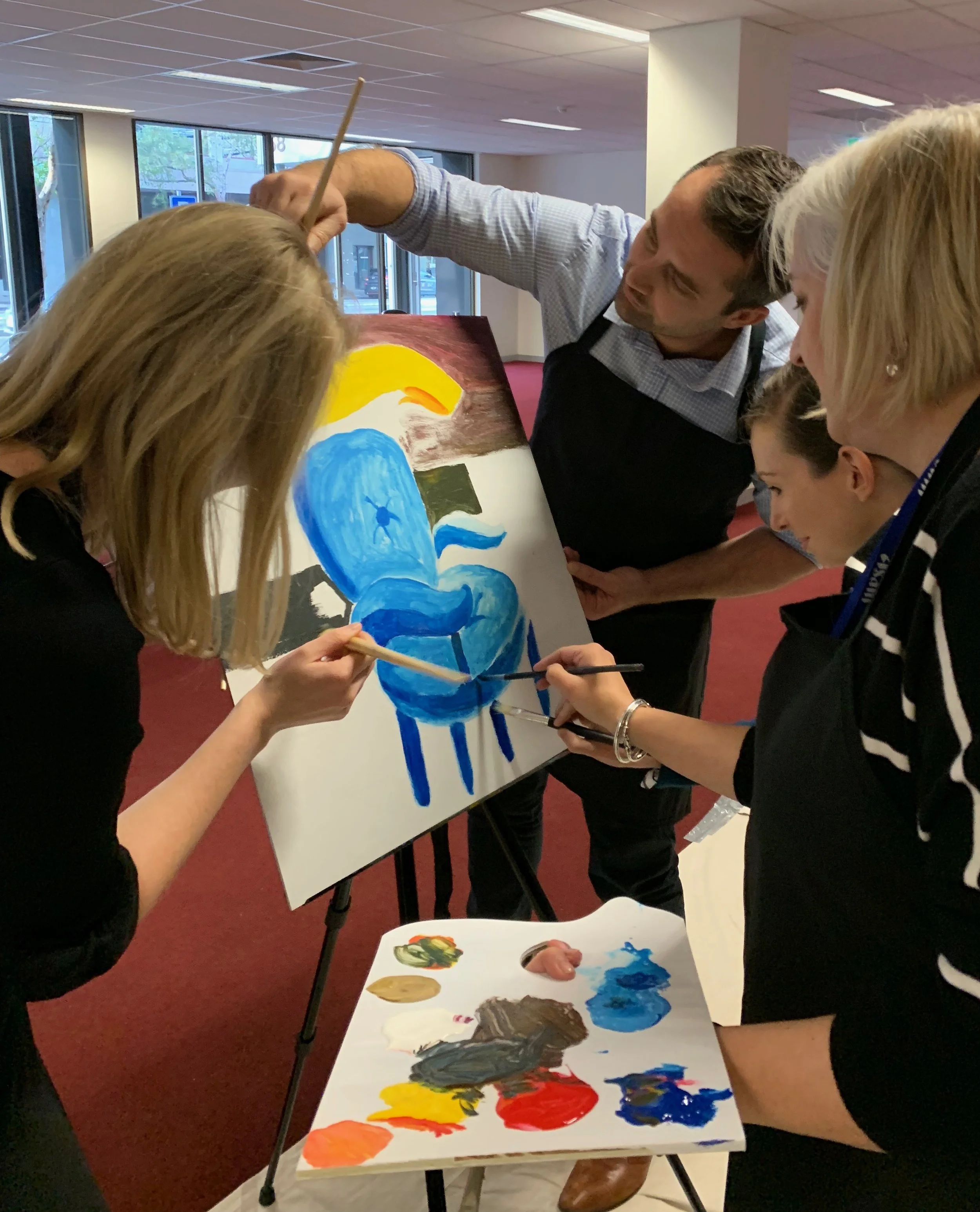 Participants painting a collaborative team mural together