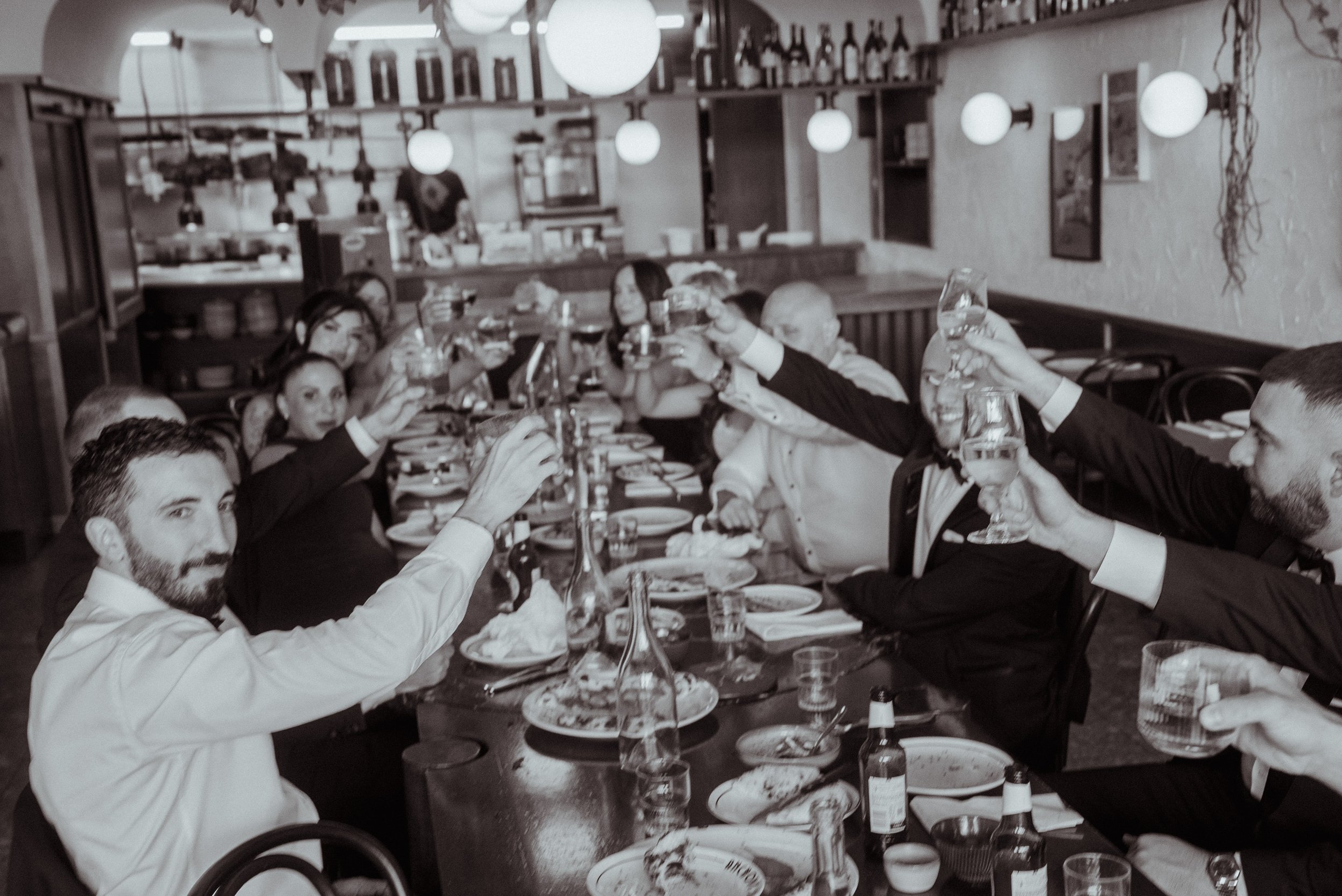 Group of people at a dinner party raising glasses for a toast in a restaurant.