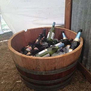Wooden barrel filled with empty glass bottles, some submerged in ice.