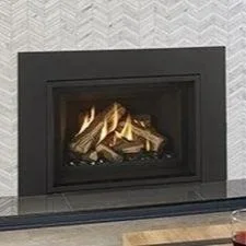 Black fireplace with a glass front, containing firewood and flames, in a room with gray textured wall.