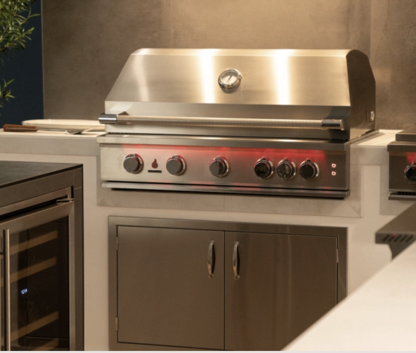 Stainless steel outdoor grill with control knobs, built-in thermometer, and a partially open lid.