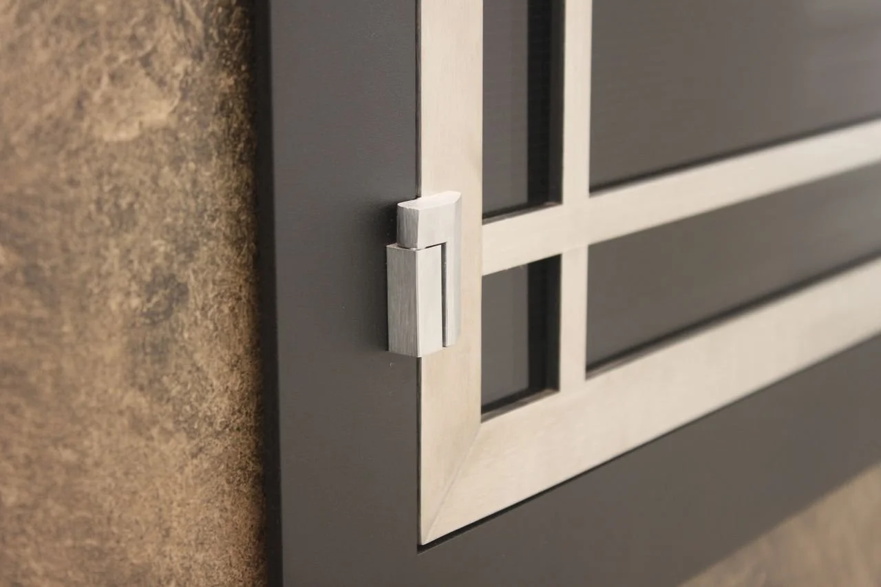 Close-up of a metallic grill or vent cover mounted on a dark wall, with a geometric design and rectangular panels.