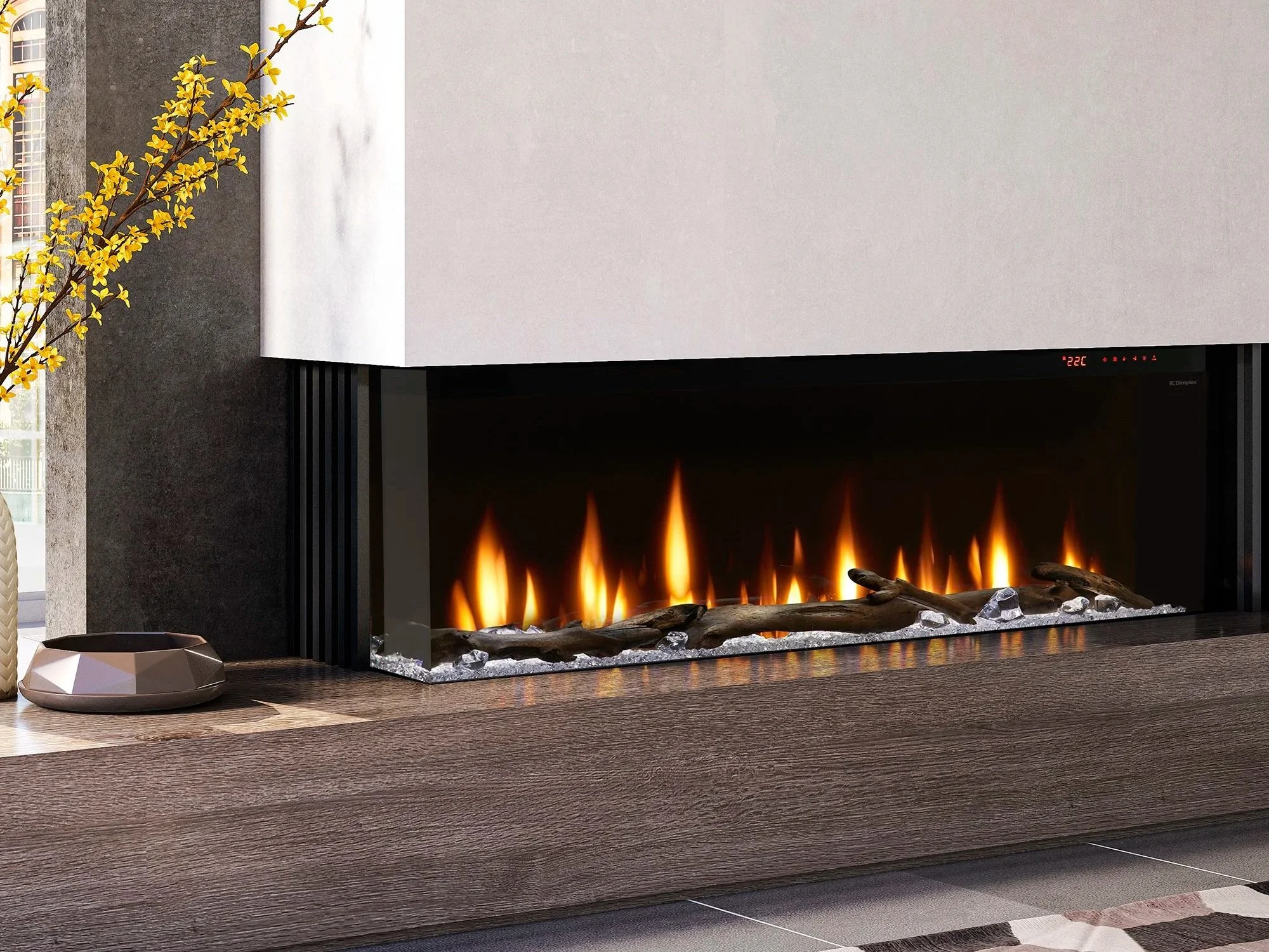 Modern fireplace with animated flames topped with driftwood, set against a wall with a wood console below, and a decorative object and yellow flowering branch on the side.