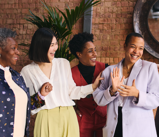 four diverse women laughing and clapping together