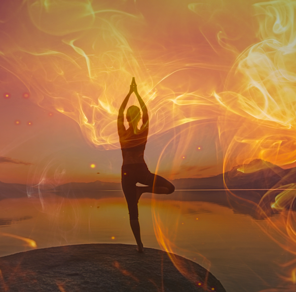 woman standing in yoga pose on rock overlooking water with fire overlay