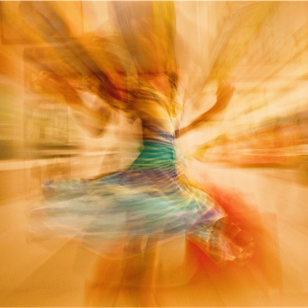 blurred image of woman twirling while dancing at somatic release event