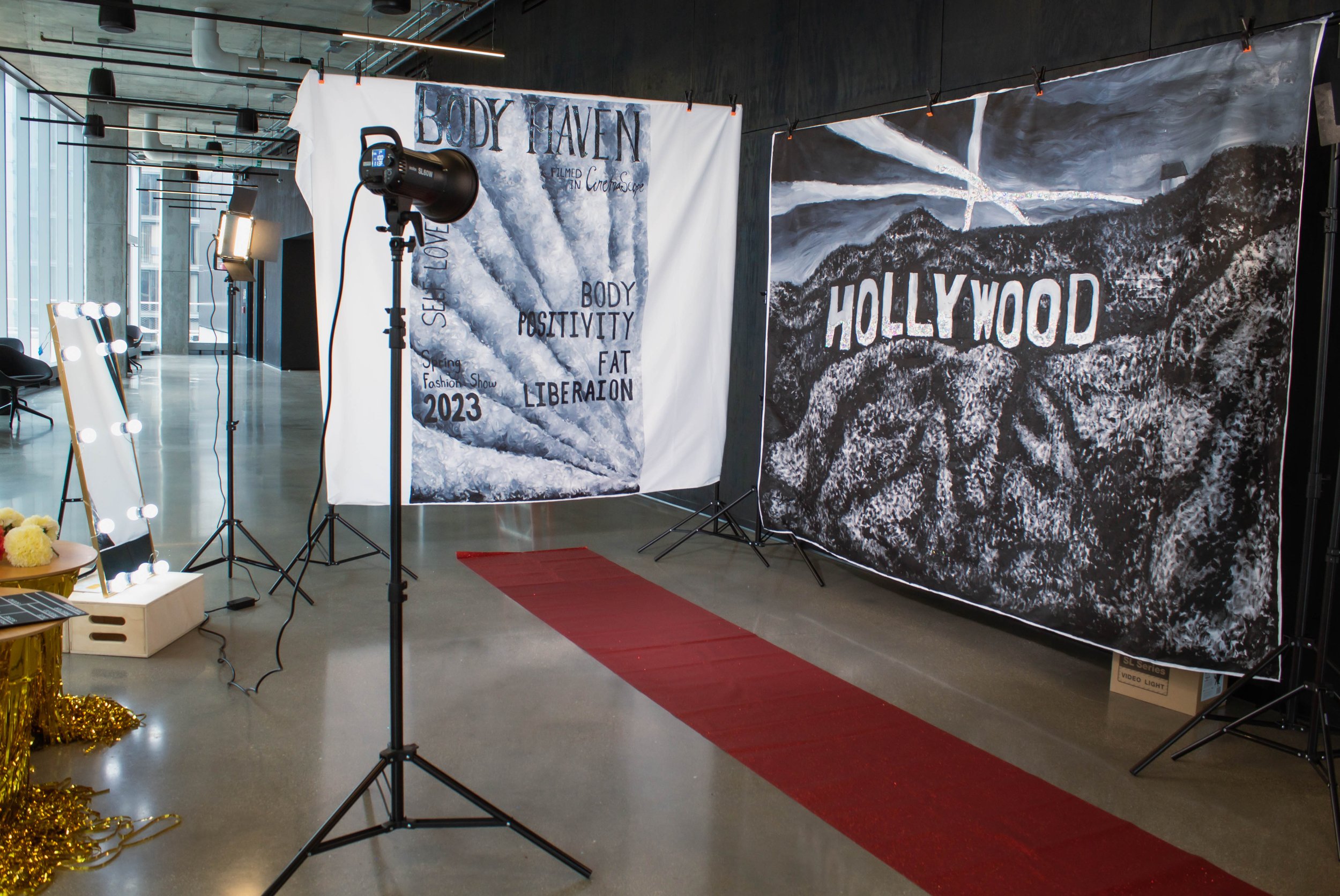Photo of a photography setup with backdrops, studio lights, and a mirror in a modern indoor space with large windows.