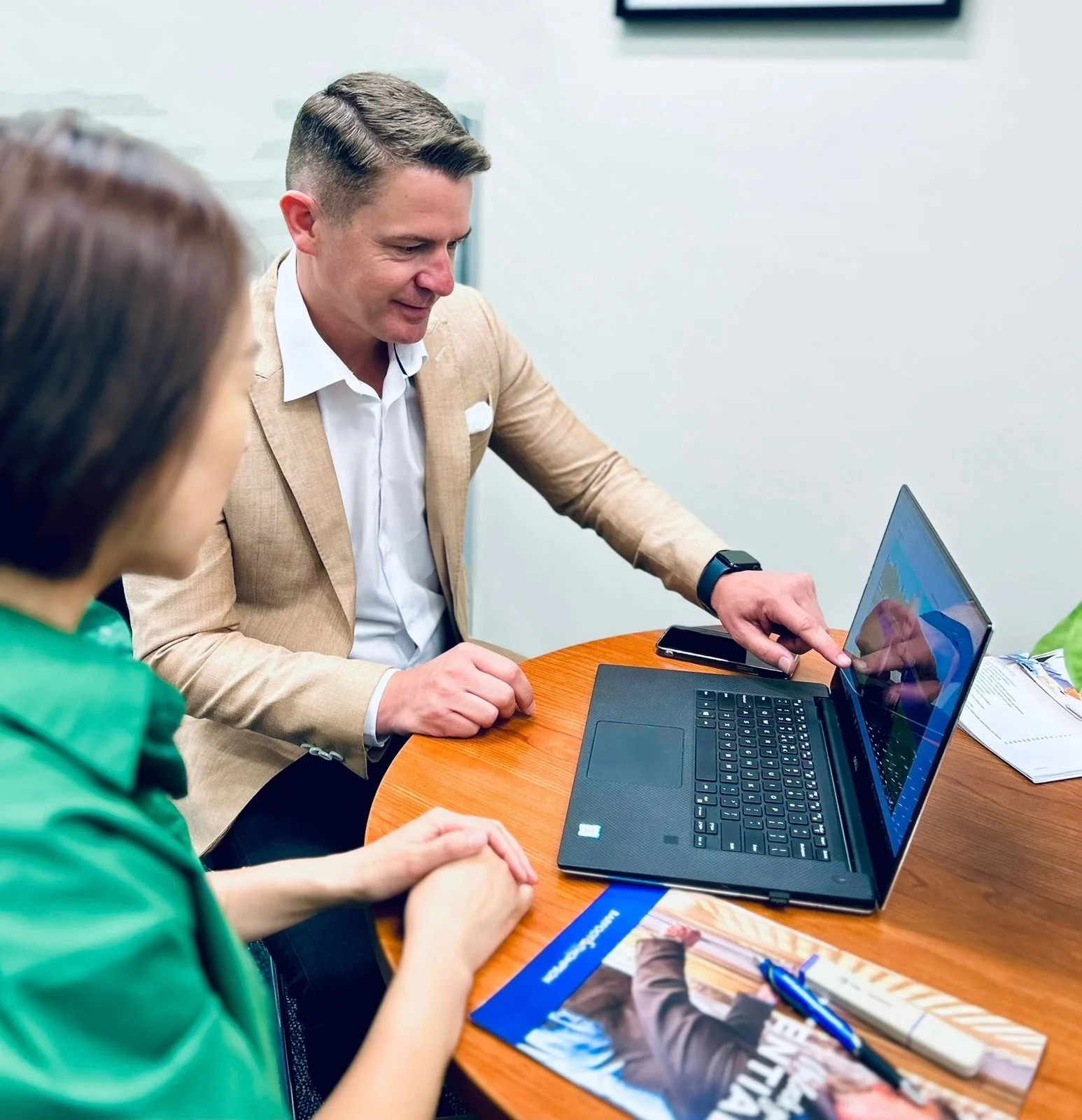 Mike Vermeulen and assistant working at a table on a laptop implementing a property marketing plan.