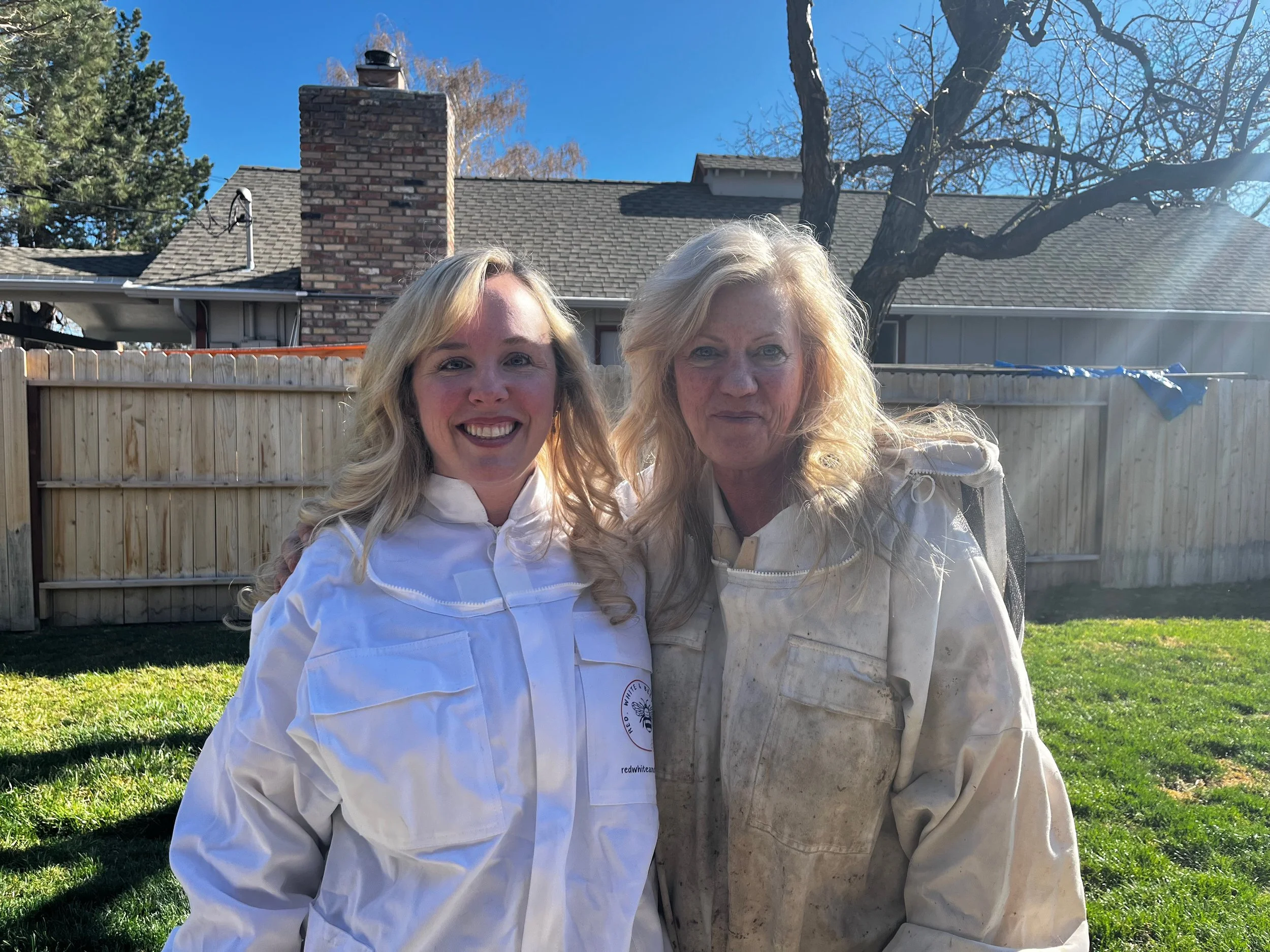 Two women in beekeeping suits.