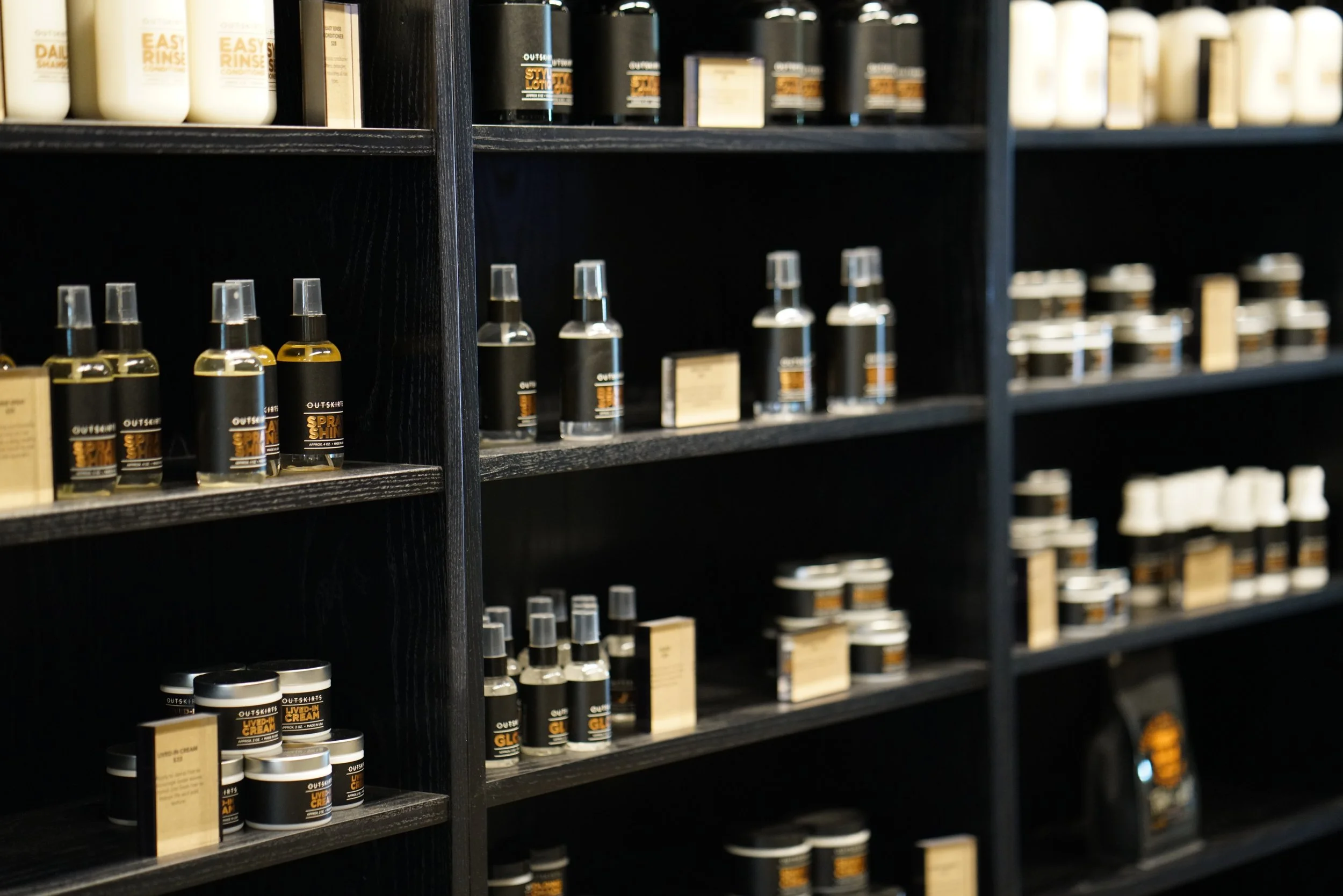 Black wooden shelves stocked with various bottles and containers of grooming or skincare products.