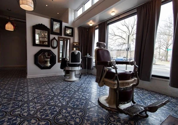 Vintage barber shop with a barber chair, mirrors, and large windows with curtains.