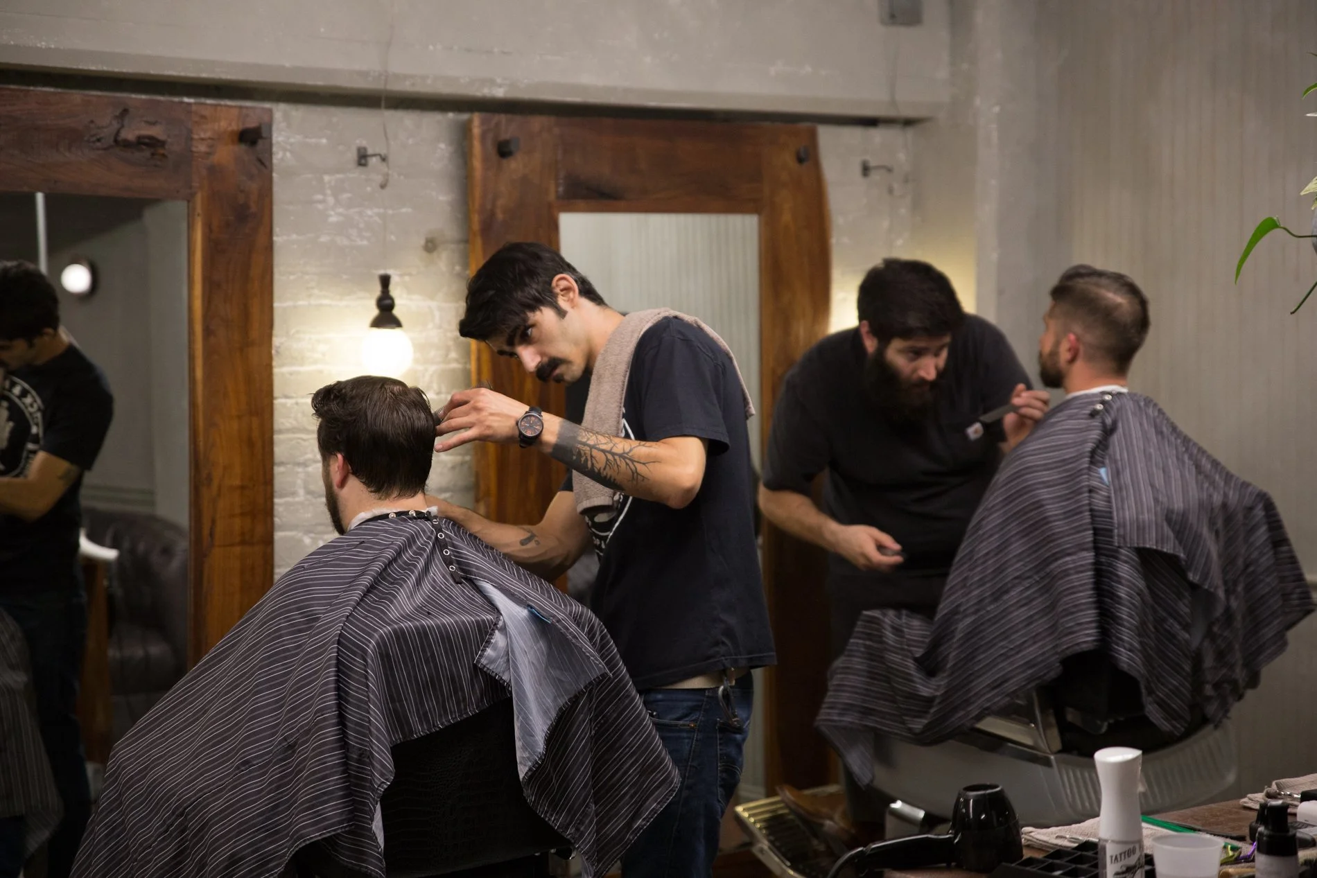 Barbers giving haircuts to clients in a modern barber shop.