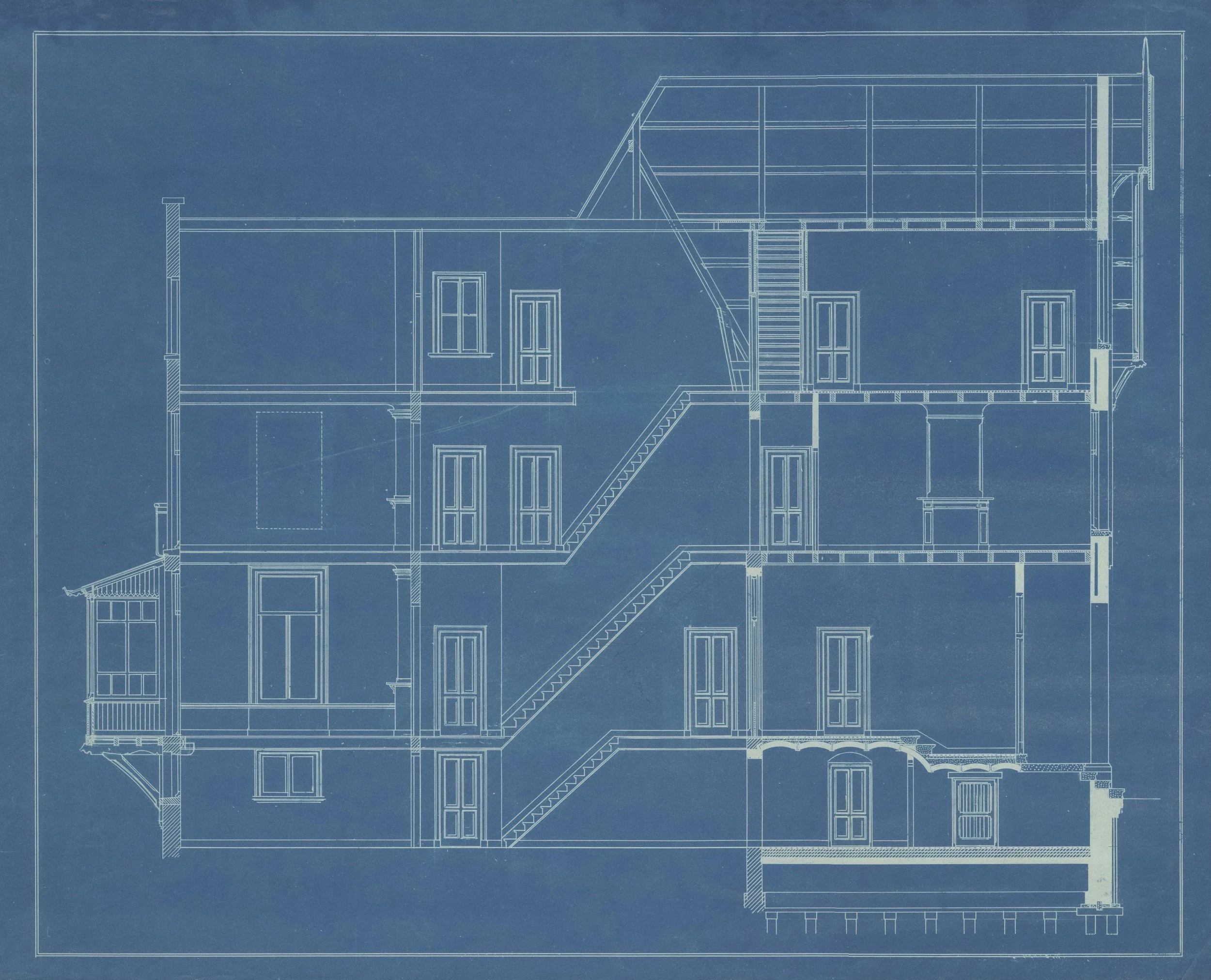 A detailed architectural blueprint of a house in white lines on a blue background, showing multiple floors and structural elements.