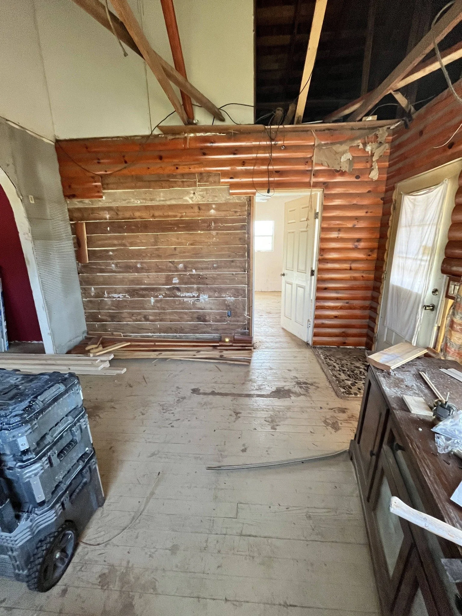 Interior room undergoing renovation, with exposed wooden walls, construction tools, and debris on the floor.