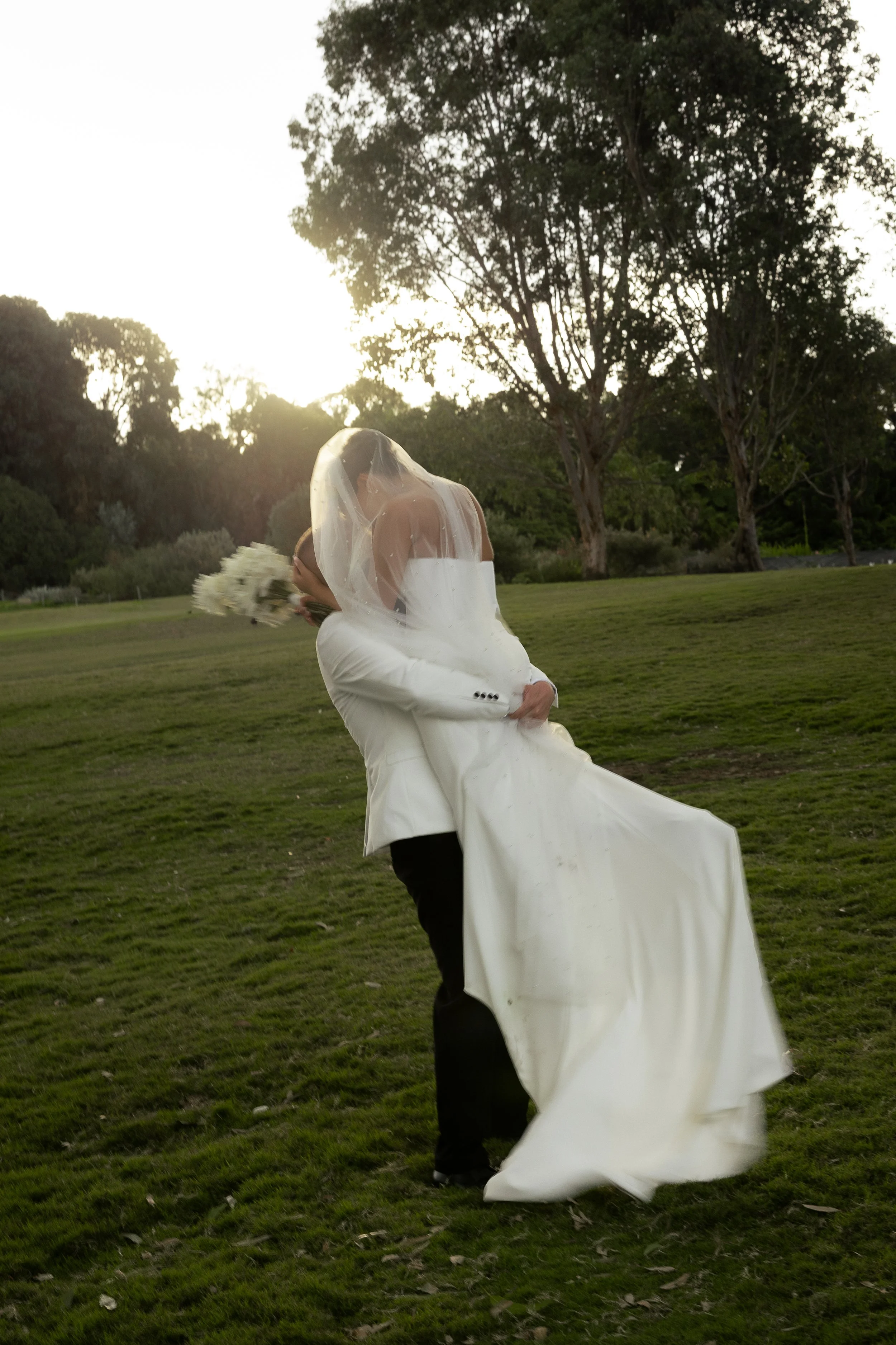 A groom is lifting his bride up as th