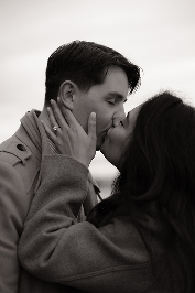 A man and woman about to kiss, holding each other's faces, in black and white.