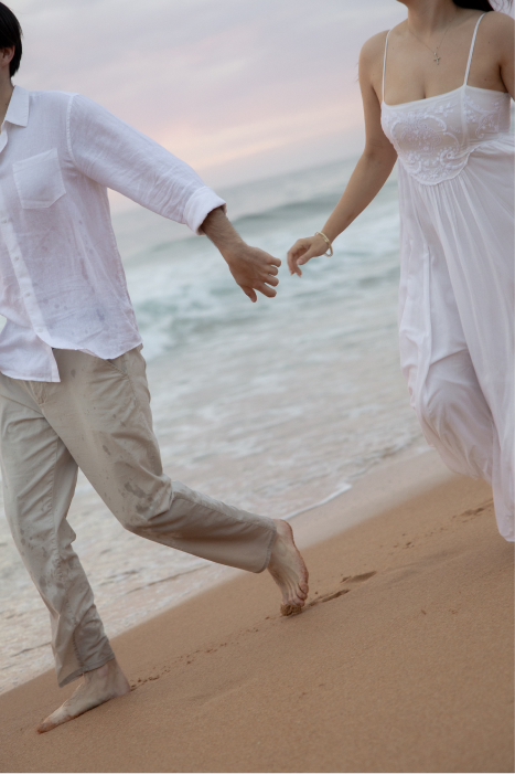 A couple holding hands while walking along the beach.