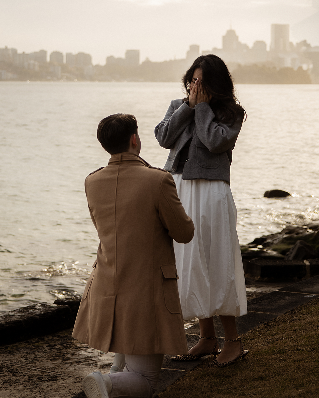 A man proposing to a woman by the water at sunset