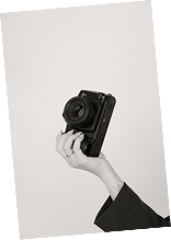 A hand holding a camera against a plain white background.