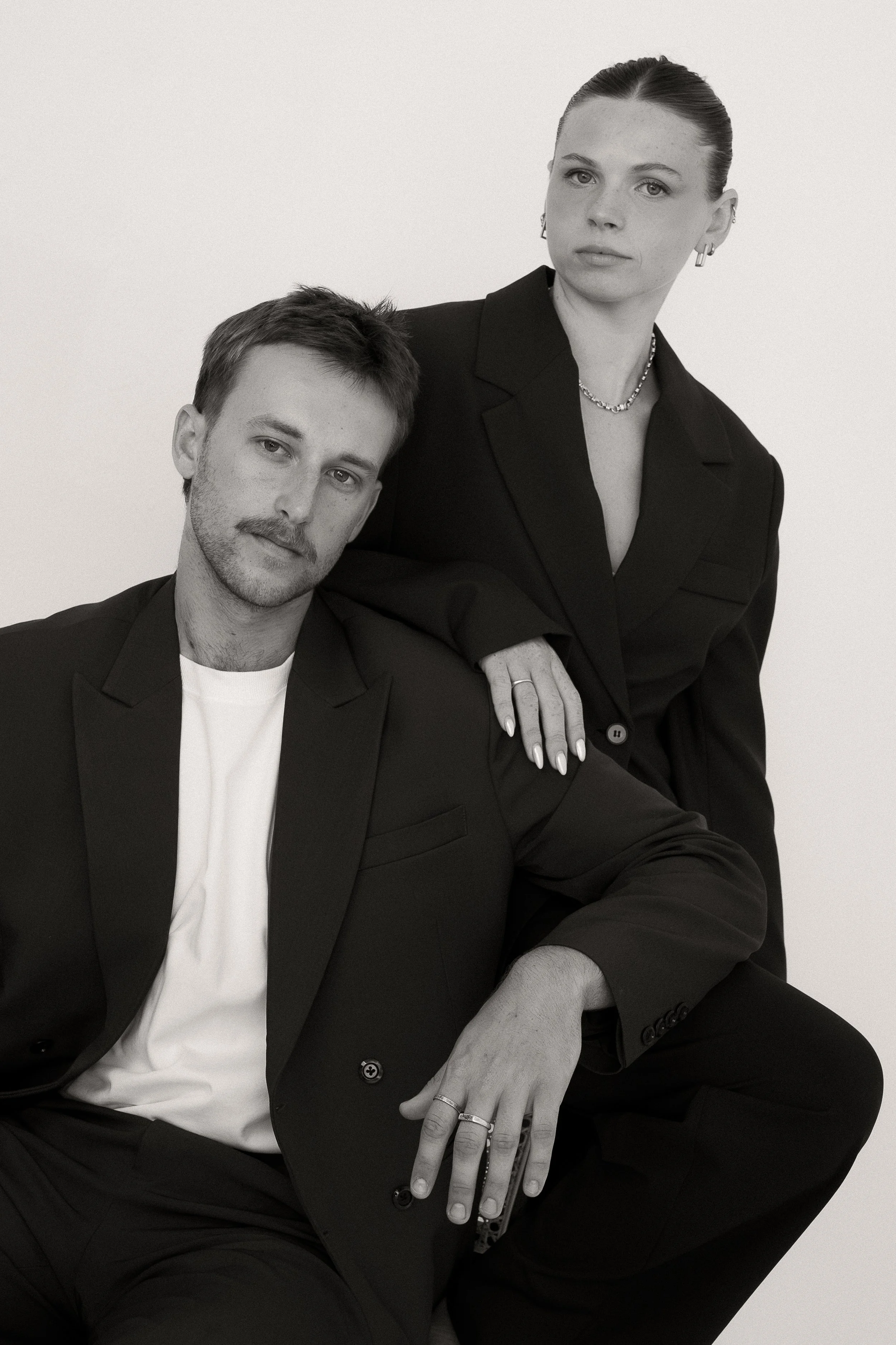Black and white portrait of a young man and woman dressed in formal attire, seated closely against a plain background.