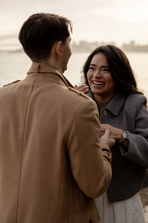 A man and woman smiling and talking outdoors during the daytime.
