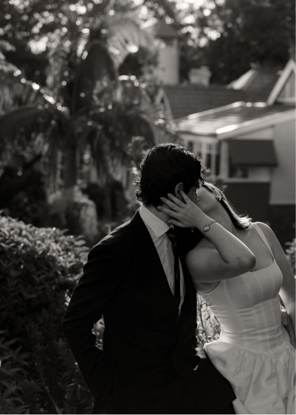 A couple dressed in formal attire sharing an intimate moment outdoors