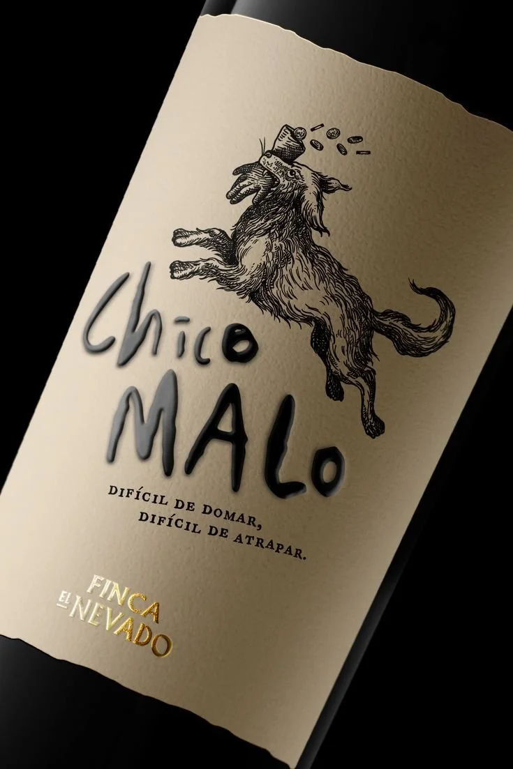 Wine bottle label with illustration of a wild boar with coins spilling from its mouth. Text reads "Chico Malo," "Difícil de dormir, difícil de atrapar," and "Finca El Nevado."