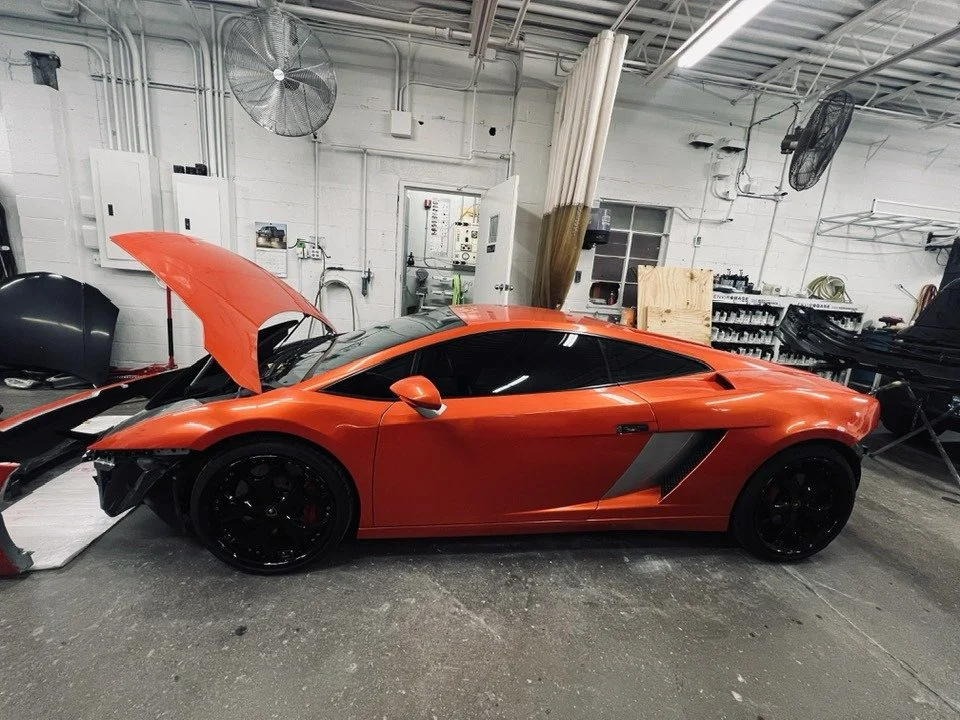 Red sports car with open hood inside a workshop.