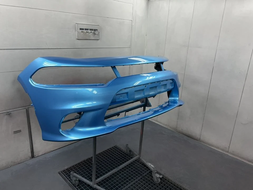 Blue car bumper on a stand in a workshop or garage.