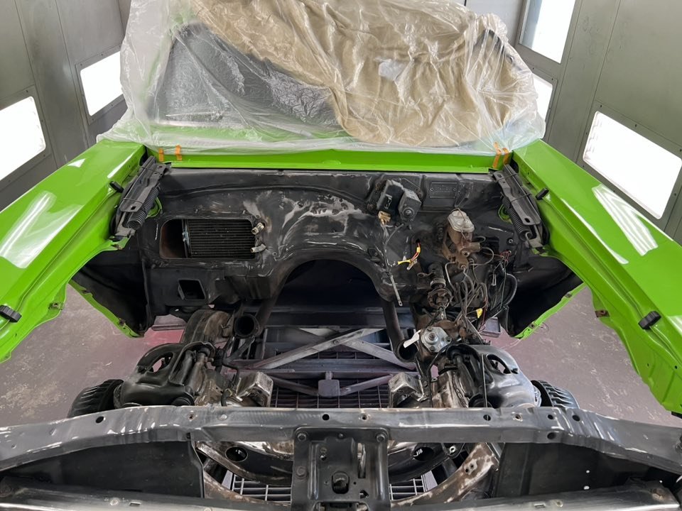 Front of a car with the hood removed, showing the engine bay and a lime green exterior.