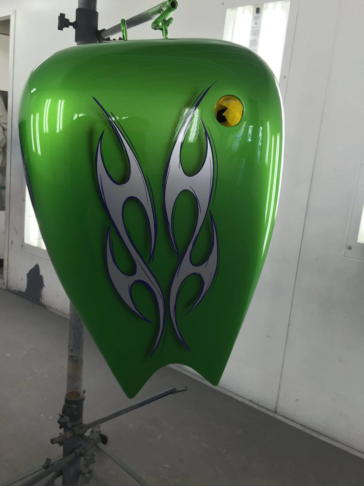 Green motorcycle gas tank with purple and silver flame graphic design.