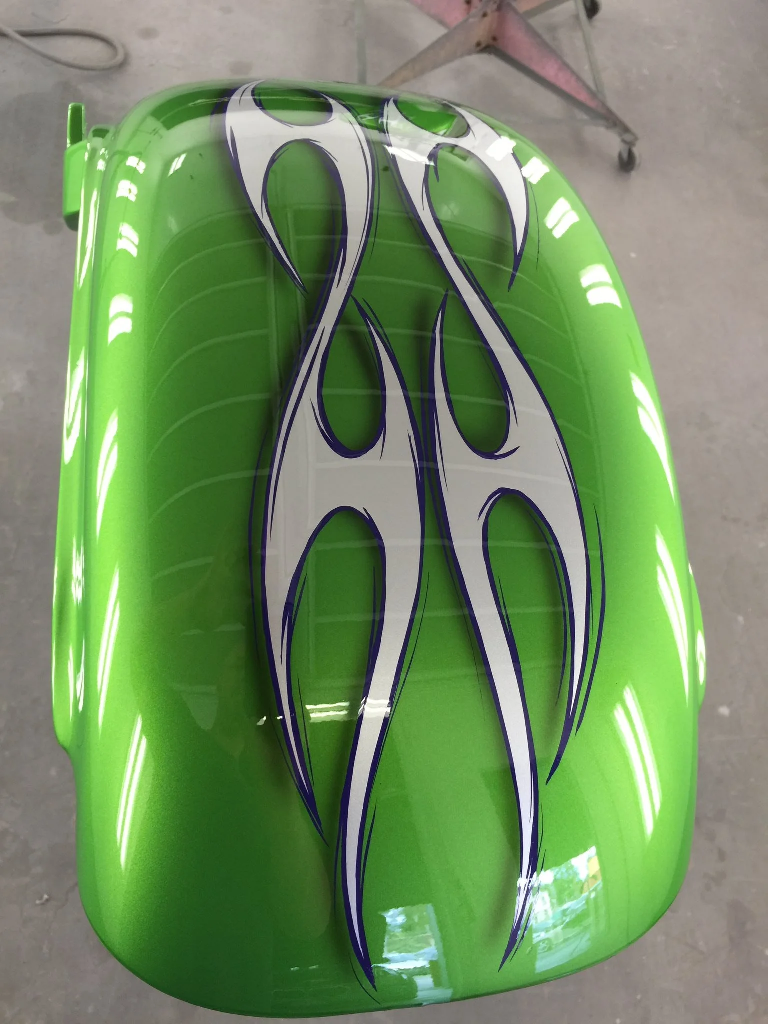 Bright green motorcycle fuel tank with black and white flame design.